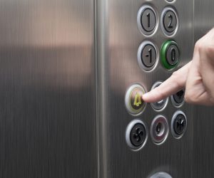 Man pressing the alarm button in the elevator with his forefinger